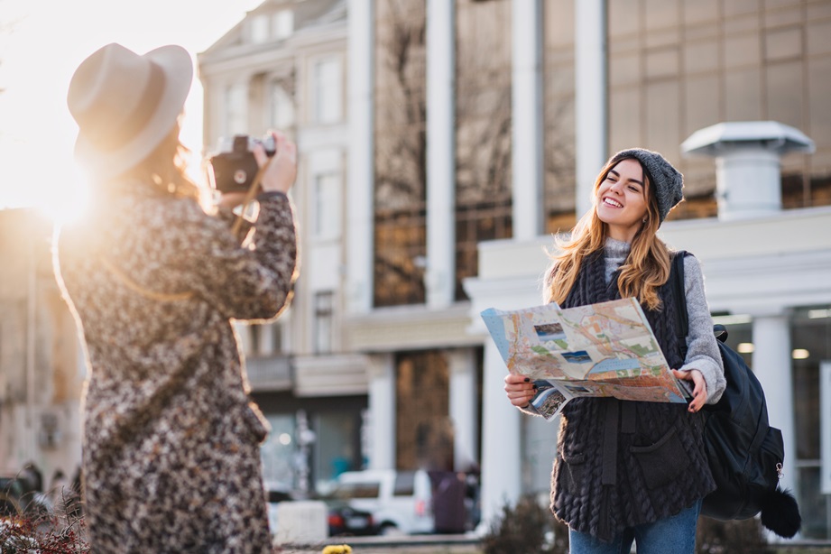 Travelling in sunny big city of fashionable joyful gilrs. Taking photo, enjoying vacation, travel with backpack, citymap. Showing true positive happy emotions, stylish look, posing to camera